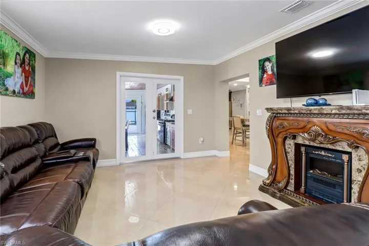 Family room featuring crown molding, hurricane proof French doors and tile floors