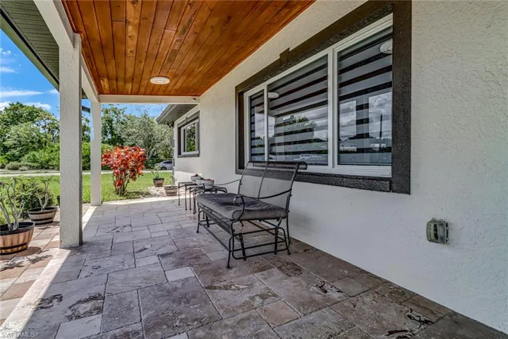 Open entry porch with travertine tile and a beautiful tongue and groove wood ceiling.