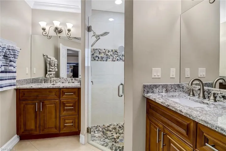 Bathroom featuring crown molding, tile flooring, vanity with extensive cabinet space, and an enclosed shower