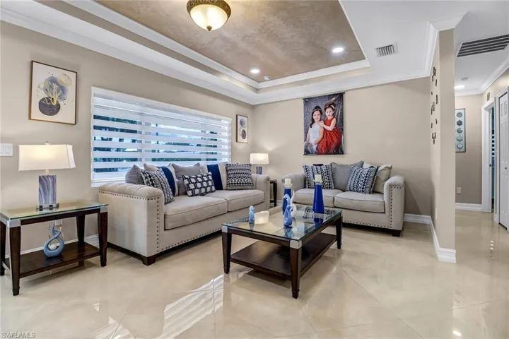 Living room with tile flooring, crown molding, and a tray ceiling