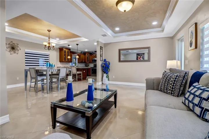 Living room with raised ceiling, crown molding, and light tile floors