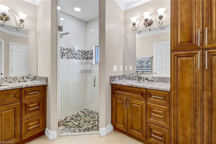 Bathroom with tile floors, an enclosed shower, crown molding, and vanity