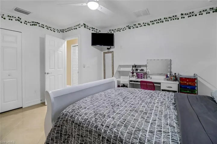 Tiled bedroom featuring ceiling fan and crown molding