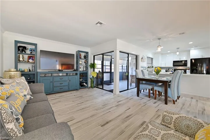 Open-concept living area with wood-finish flooring, crown molding, and recessed lighting