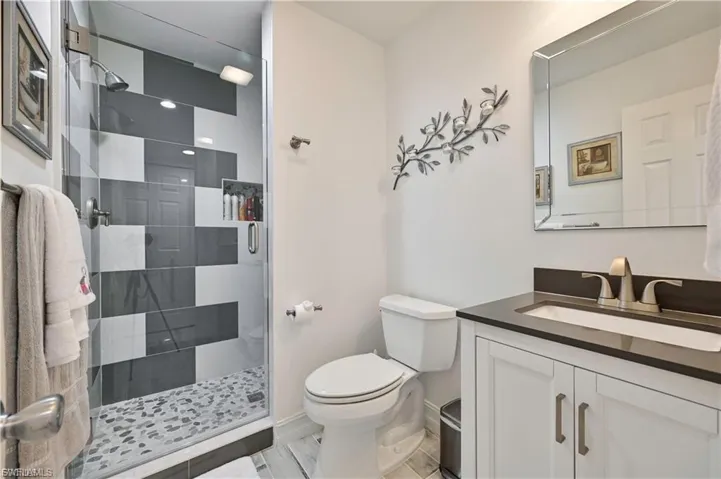Contemporary bathroom featuring a walk-in shower with patterned tile, a built-in shower niche, and a pebble-finish shower floor