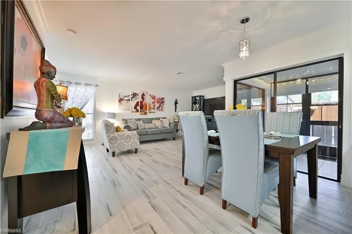 Open-concept living space with light wood-finish flooring, crown molding, and a sliding glass door