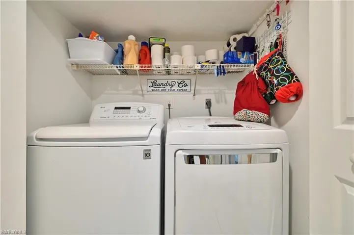 Dedicated laundry area featuring white washer and dryer units, wire shelving, and overhead lighting
