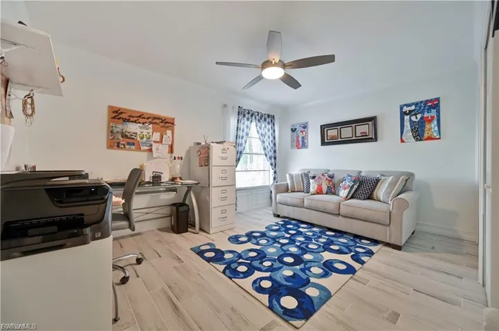 Bright room featuring wood-finish flooring, a ceiling fan with integrated lighting, and a window with blinds