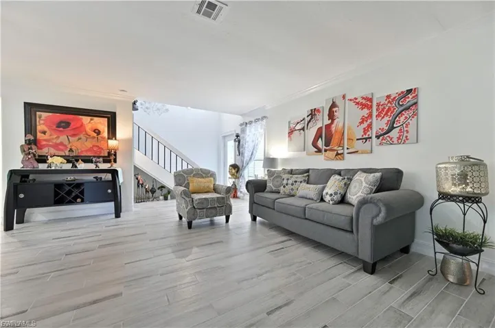 Open-concept living area featuring light wood-finish flooring, white walls, and crown molding