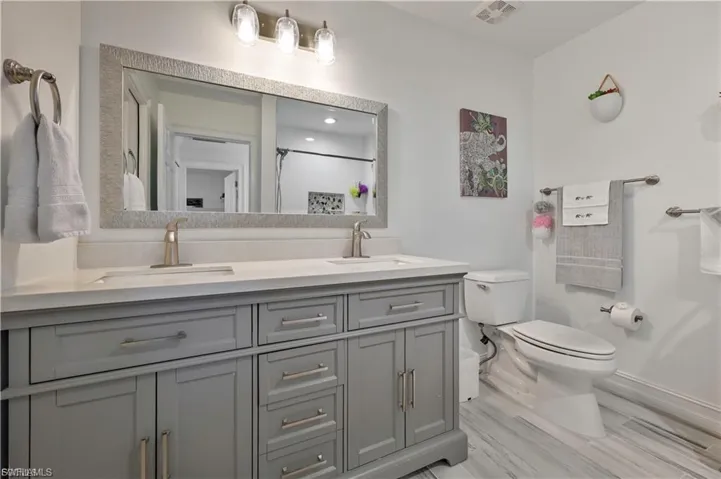 Bathroom featuring a dual vanity with a light gray cabinet base, brushed nickel hardware, and a white countertop