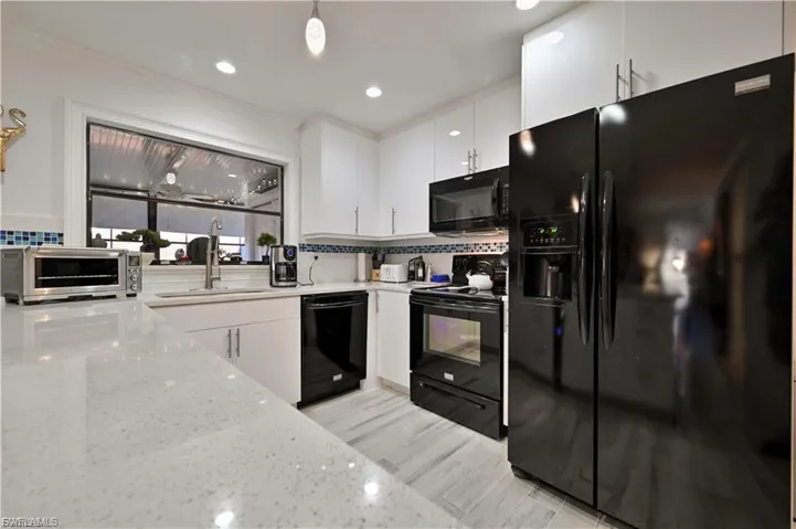 Kitchen featuring white upper and lower cabinetry, light-toned countertops, and a white subway tile backsplash with blue accent tiles