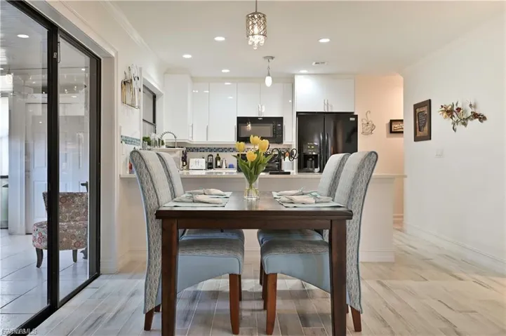 Open-concept dining area featuring wood-finish flooring, a kitchen pass-through, and sliding glass doors