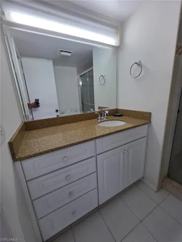 Bathroom with light tile patterned floors, vanity, and a stall shower