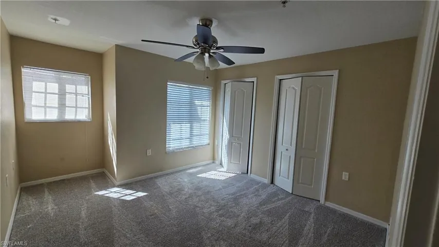 Unfurnished bedroom featuring two closets, multiple windows, and carpet flooring