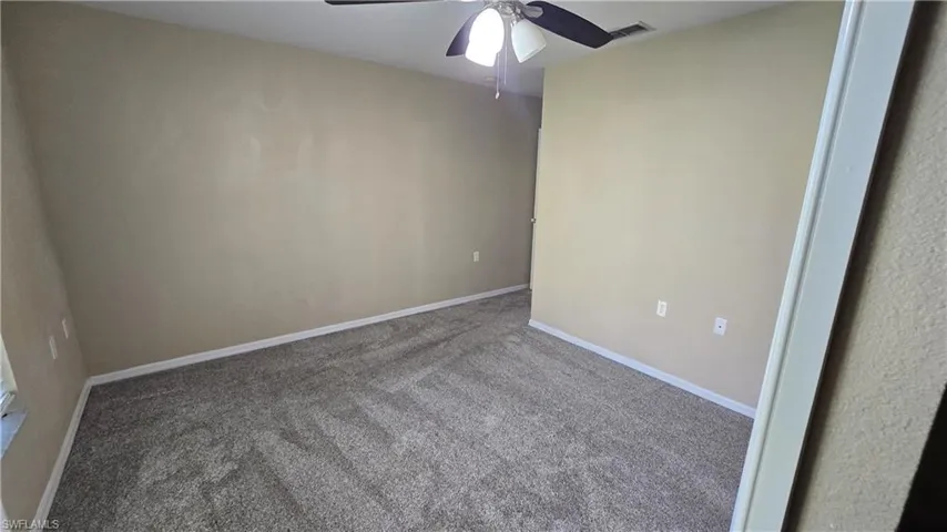 Carpeted spare room with baseboards and a ceiling fan