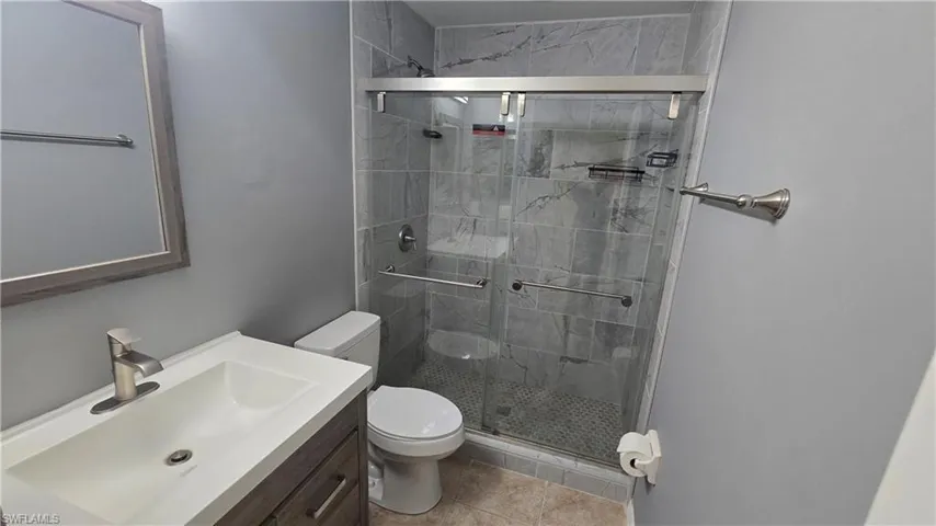 Full bathroom with vanity, a stall shower, and light tile patterned flooring