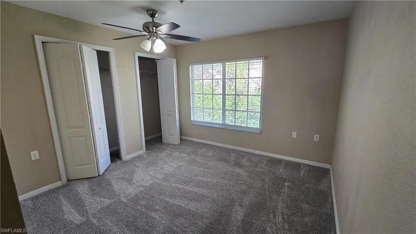 Unfurnished bedroom with two closets, carpet floors, and ceiling fan