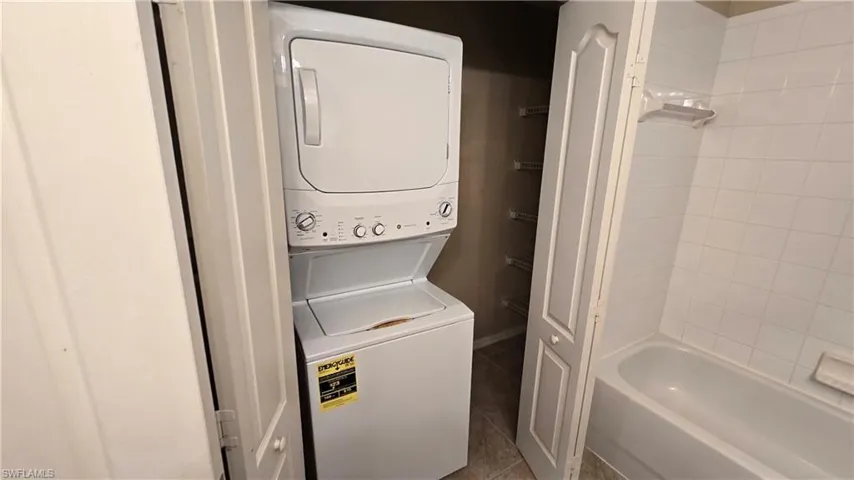 Laundry room featuring dark tile patterned flooring and estacked washer and dryer