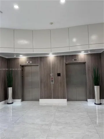 Elevator lobby featuring polished light-toned tile flooring, wood-finish wall panels, and recessed ceiling lighting