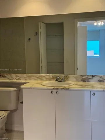 Vanity with a polished stone countertop featuring an integrated sink and chrome faucet