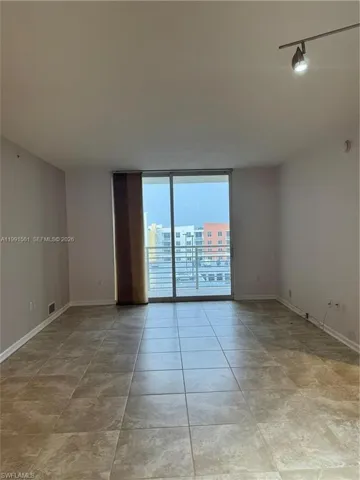 Spacious room featuring tile flooring, sliding glass doors, and a balcony with metal railings