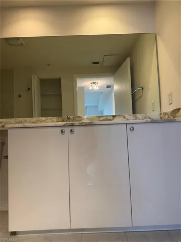 Contemporary vanity featuring a white finish, circular chrome hardware, and a stone countertop