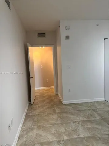 Tiled flooring extending through a doorway, featuring white baseboards and light-toned walls