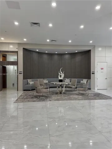 Spacious common area featuring large format polished tile flooring, recessed ceiling lighting, and a curved accent wall with vertical paneling