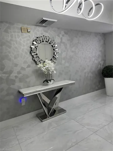 Textured accent wall featuring a console table with a polished chrome base and a stone-finish top