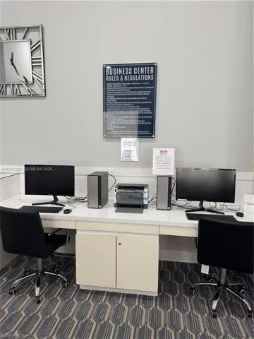 Business center featuring two computer workstations, a central printer, and ample desk space