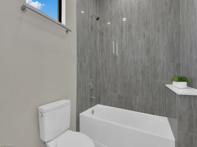 Bathroom featuring tiled shower / bath combo and toilet