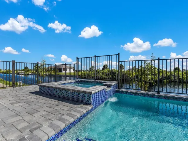 View of pool with a water view, an in ground hot tub, and pool water feature