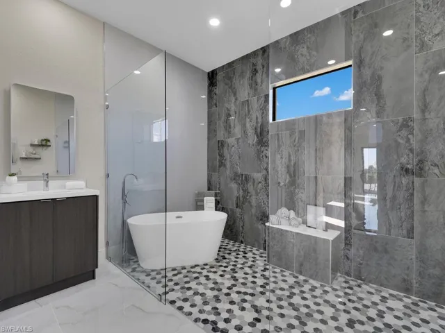 Bathroom featuring vanity, tile walls, and shower with separate bathtub