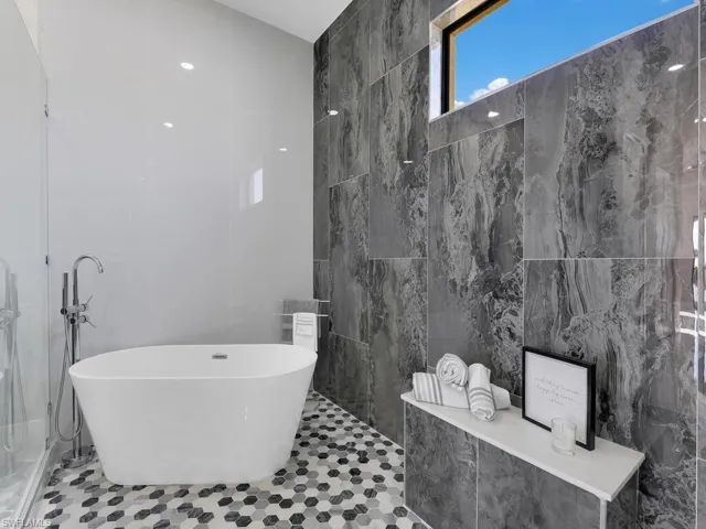 Bathroom featuring tile patterned flooring, a tub, and tile walls