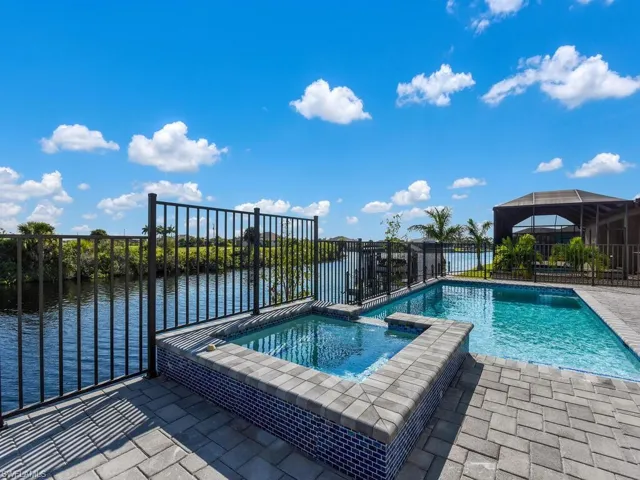 View of swimming pool featuring a lanai, a water view, and an in ground hot tub