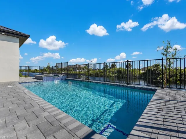 View of swimming pool featuring a water view, an in ground hot tub, and a patio area