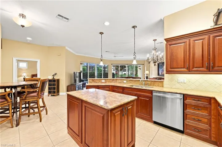 Expansive kitchen featuring a central island, wood-finish cabinetry, granite countertops, stainless steel appliances, and tile flooring