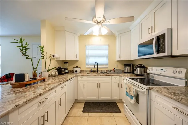Kitchen featuring white cabinetry, stone-finish countertops, and tile flooring