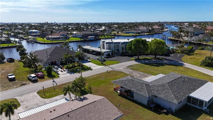 Waterfront property featuring a private boat dock, lush palm trees, and a paved driveway