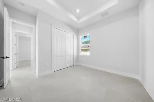 Unfurnished bedroom with a raised ceiling, a closet, and recessed lighting