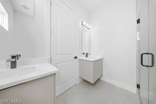 Full bathroom with two vanities, a shower stall, and concrete floors