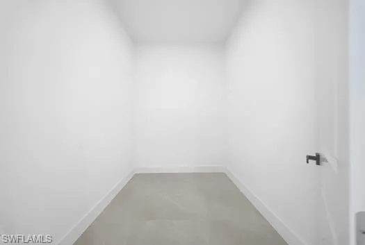 Unfurnished room with baseboards and concrete flooring