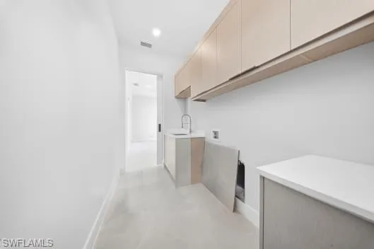 Washroom featuring washer hookup, cabinet space, and finished concrete floors