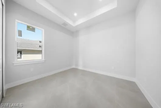 Unfurnished room featuring a raised ceiling, concrete floors, and recessed lighting