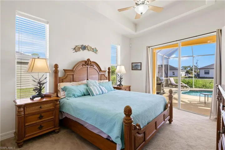 Carpeted bedroom with ceiling fan, access to exterior, multiple windows, and a sunroom