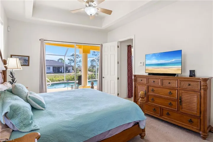 Bedroom featuring a sunroom, access to outside, carpet floors, a raised ceiling, and ceiling fan