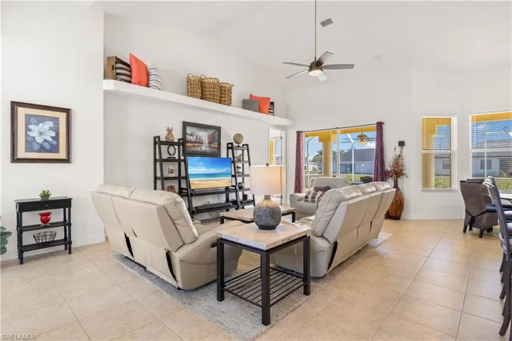 Living area with light tile patterned flooring, high vaulted ceiling, and ceiling fan