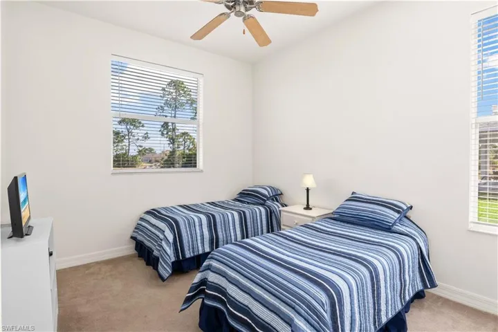Bedroom featuring light carpet, multiple windows, and ceiling fan