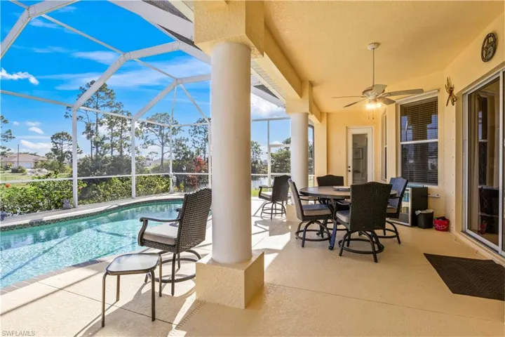View of patio with a sunroom, ceiling fan, an outdoor pool, glass enclosure, and outdoor dining space
