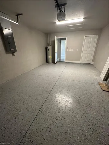Garage with a garage door opener, water heater, and electric panel